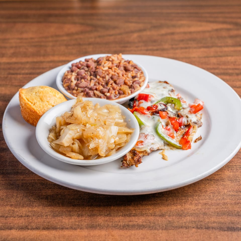 DeAngelo's Italian meal with chicken, peppers, onions, rice, beans, and cornbread on a white plate.